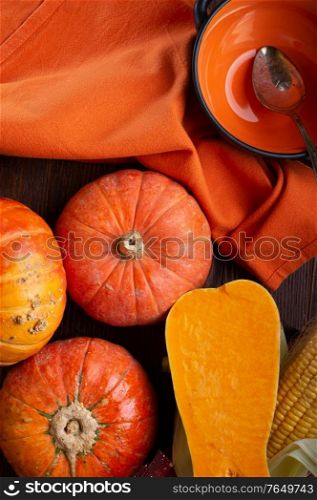 ripe orange pumkins served at wooden brown table with orange bowl and corn. flat lay. healthy life concept