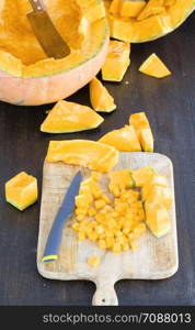 ripe orange pumpkin cut into square and other pieces, close-up of raw food for cooking. ripe orange pumpkin cut