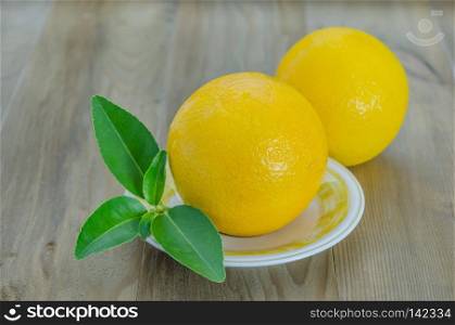 ripe orange with leaves on dish over wooden background. orange with leaves on dish 
