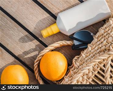 Ripe oranges, wicker basket, sunblock and sunglasses. Top view, close-up. Concept of leisure and travel. Ripe oranges, wicker basket and sunglasses. Top view