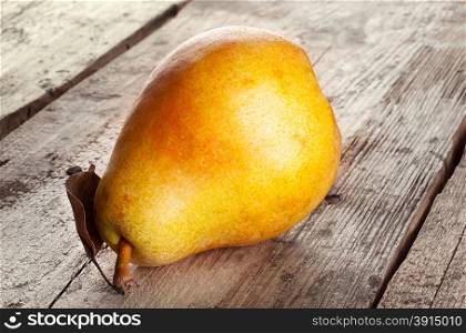 Ripe pear with dry leaf on wooden background