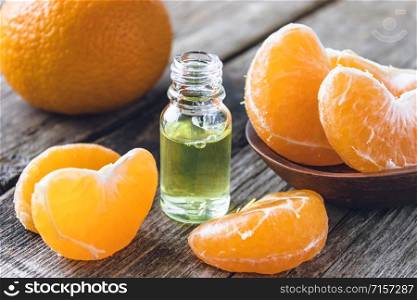 Ripe peeled slices of tangerine without peel and a bottle of essential oil with tangerine on the table. Citrus fruits, tangerines or oranges. Alternative medicine. Ripe peeled slices of tangerine without peel and a bottle of essential oil with tangerine on the table.