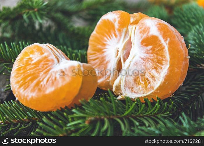 Ripe peeled slices of tangerine without peel lie on the green branches of a Christmas tree. Citrus fruits, tangerines or oranges. Close-up.. Ripe peeled slices of tangerine without peel lie on the green branches of a Christmas tree.