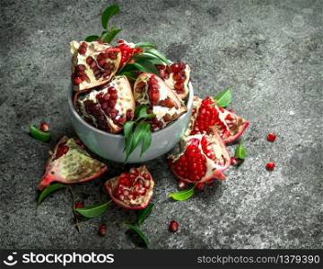 Ripe pieces of pomegranate in a bowl. On a rustic background.. Ripe pieces of pomegranate in a bowl.