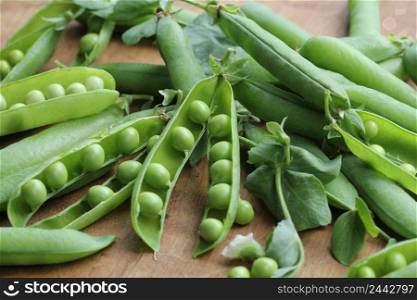 Ripe pods of green peas, fresh green peas on wooden table, close up .. Ripe pods of green peas, fresh green peas on wooden table, close up