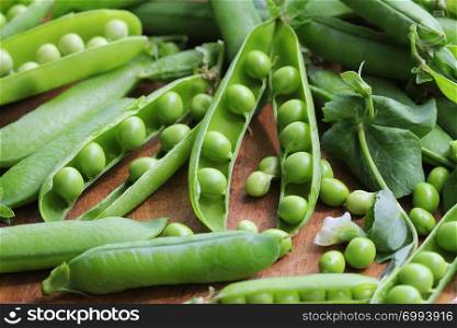 Ripe pods of green peas, fresh green peas on wooden table, close up .. Ripe pods of green peas, fresh green peas on wooden table, close up