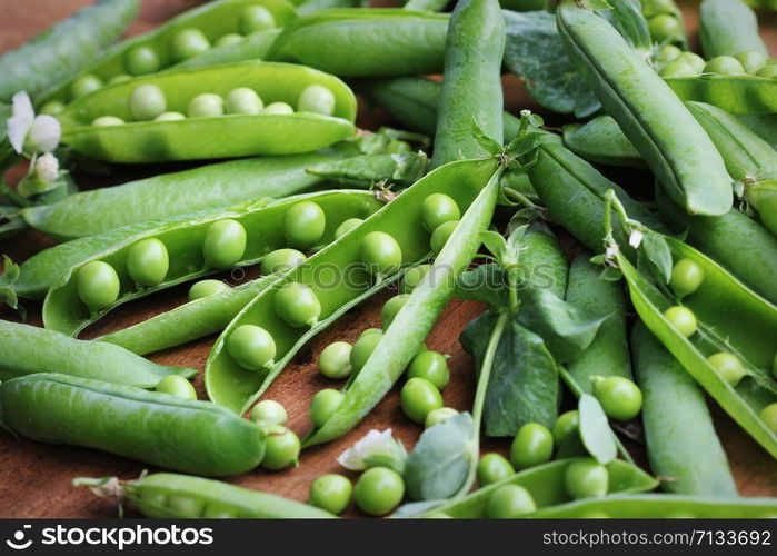 Ripe pods of green peas, fresh green peas on wooden table, close up .. Ripe pods of green peas, fresh green peas on wooden table, close up