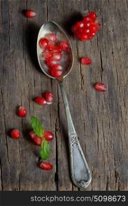 Ripe pomegranate and spoon on wooden table