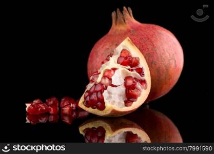 Ripe pomegranate fruit with leaves on black background