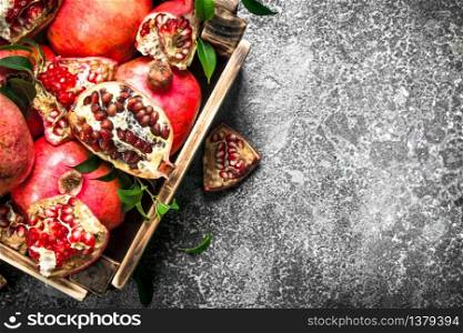 Ripe pomegranates in a box. On a rustic background.. Ripe pomegranates in a box.