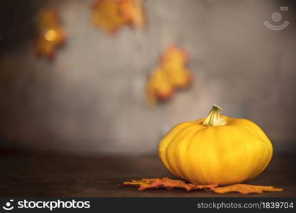 ripe pumpkin and autumn leaves on wooden table on brown background with copy space decorative colorful design space for text. ripe pumpkin and autumn leaves on wooden table on brown background with copy space decorative colorful design