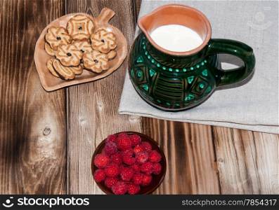 Ripe raspberry and milk jug on the old wooden table top
