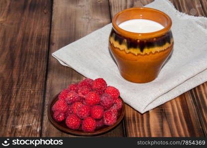 Ripe raspberry and milk jug on the old wooden table top