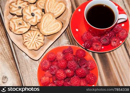 Ripe raspberry coffee cup and cookies on the old wooden table top