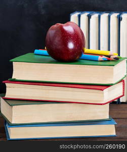 ripe red apple lying on a stack of books, abstract background back to school