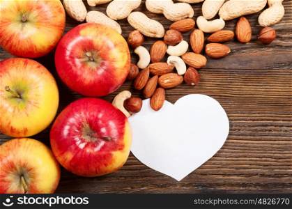Ripe red apples and different nuts on a wooden background. Top view. Vegan concept.