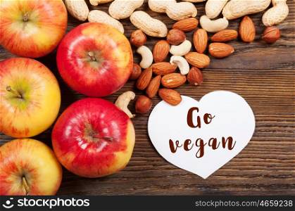 Ripe red apples and nuts on a wooden background. Top view. Vegan concept.