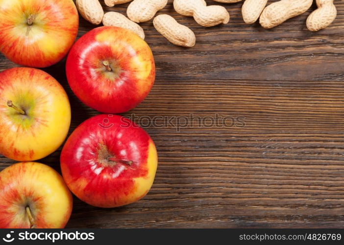 Ripe red apples and peanuts on a wooden background. Top view.