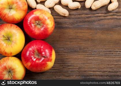 Ripe red apples and peanuts on a wooden background. Top view.