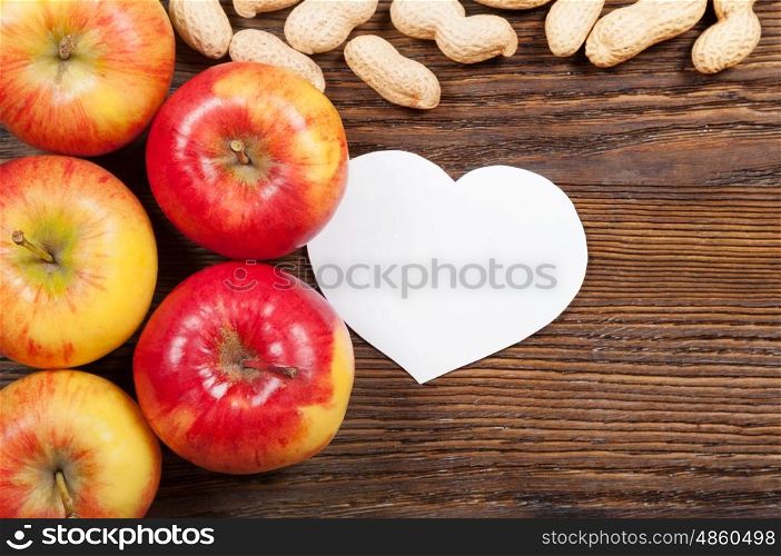 Ripe red apples and peanuts on a wooden background. Top view. Vegan concept.