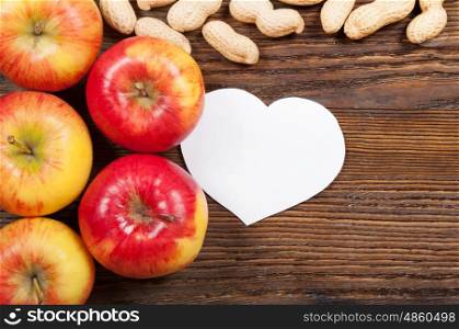 Ripe red apples and peanuts on a wooden background. Top view. Vegan concept.