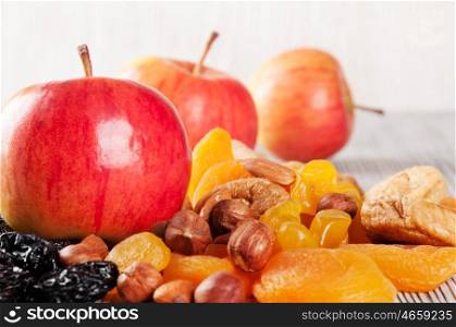 Ripe red apples on a wooden background. Juicy apples, nuts and dried fruits on a table.