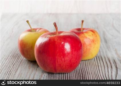 Ripe red apples on a wooden background. Three juicy apples on a table.