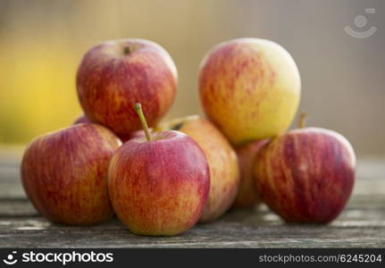 Ripe red apples on a wooden table, on green outdoor background
