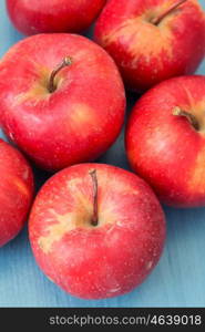 Ripe red apples on blue table close up