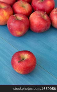 Ripe red apples on blue table close up