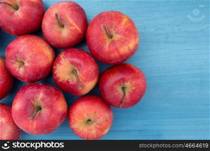 Ripe red apples on blue table close up