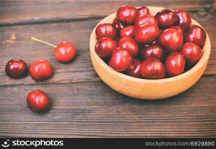 ripe red cherry in a wooden bowl, vintage toning