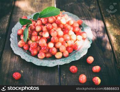 Ripe red cherry in an iron plate, top view