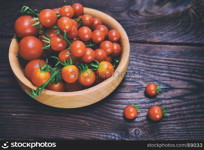 Ripe red cherry tomatoes in a wooden bowl, close up