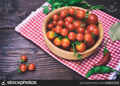 Ripe red cherry tomatoes in a wooden bowl, vintage toning