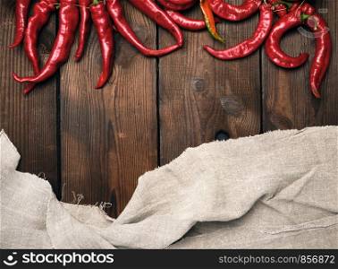 ripe red chili peppers on a brown wooden vintage background from boards, copy space