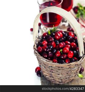Ripe red cranberries in basket and juice on wooden background