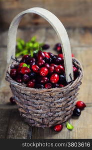 Ripe red cranberries in basket on wooden background