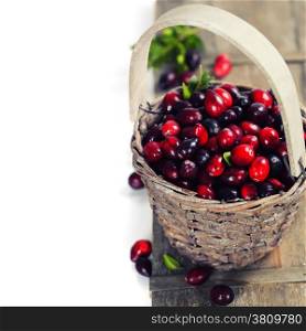 Ripe red cranberries in basket on wooden background