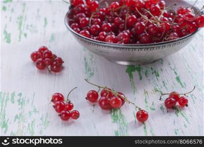 Ripe red currants in an old metal plate on wooden background.. Ripe red currants in a metal plate