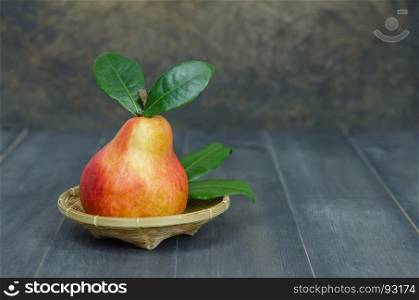 Ripe red pears. Ripe red pears with green leaves on basket over wooden table