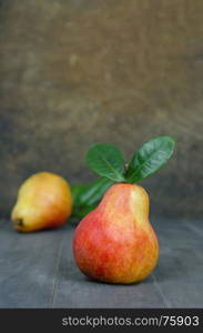 Ripe red pears. Ripe red pears with green leaves on wooden table