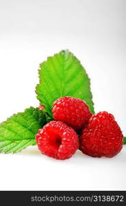 Ripe red raspberries with green leaves close up