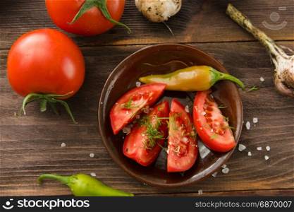 Ripe red sliced tomatoes, hot chili peppers, garlic on a wooden table