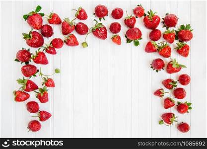 Ripe red strawberries scattered on a white wooden table. Background with strawberries, place for text.. Ripe red strawberries scattered on a white wooden table. Background with strawberries.