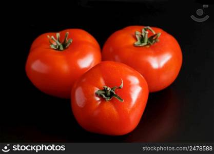 Ripe red tomatoes on a black background. Organic farm vegetables for a healthy diet.. Ripe red tomatoes on a black background. Farm vegetables for a healthy diet.
