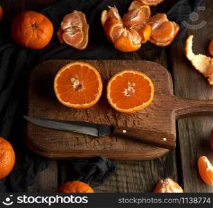 ripe round tangerines and cut in half on an old vintage cutting board. Healthy vegetarian food. Citrus fruit.