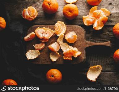 ripe round tangerines and cut in half on an old vintage cutting board. Healthy vegetarian food. Citrus fruit, top view