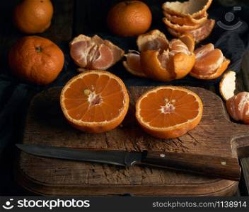 ripe round tangerines and cut in half on an old vintage cutting board. Healthy vegetarian food. Citrus fruit.