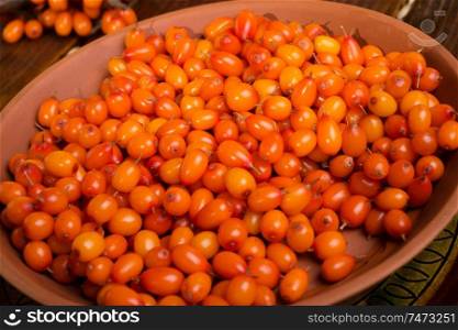 ripe sea buckthorn berries in bowl on wooden table. close up. 